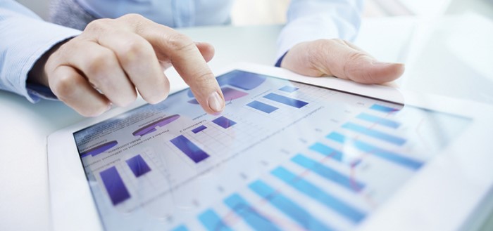 Man's hand using tablet with view of charts and graphs